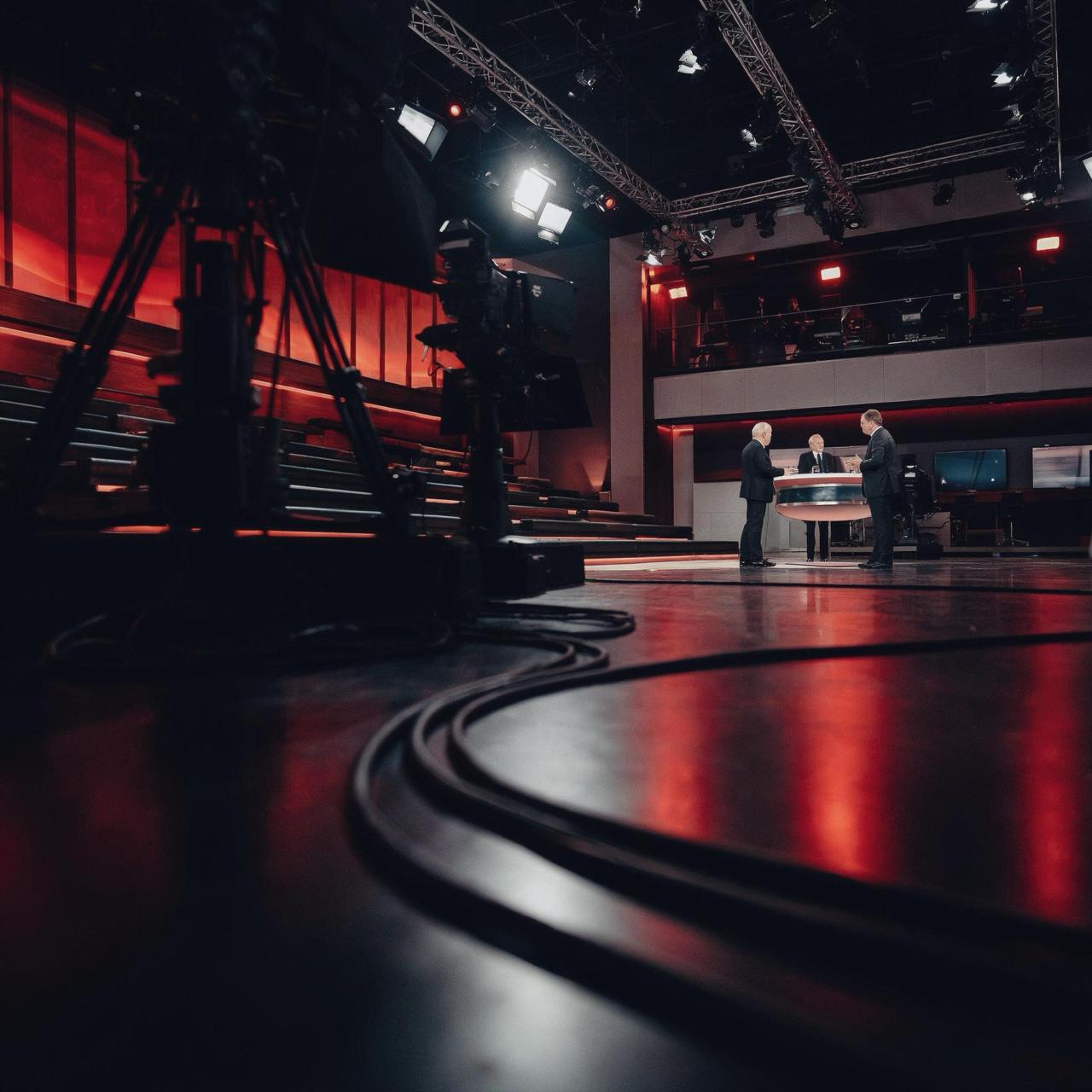 TV-Studio von Studio Newsroom: Kamera im Vordergrund, Talk-Set mit drei Personen, Lichttraversen und Regie
